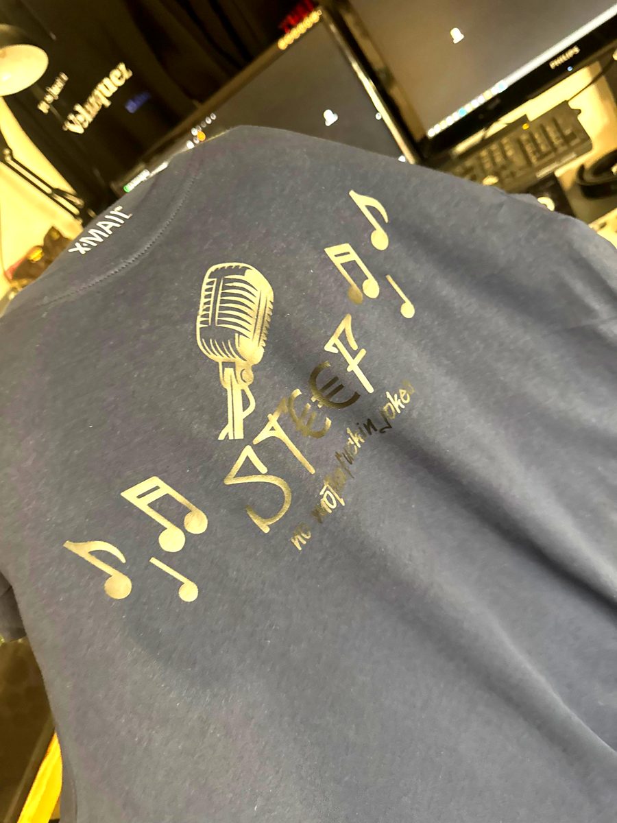 Donkerblauw shirt met gouden microfoon, muzieknoten en de naam Steef
